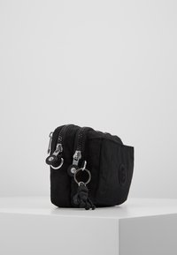 Zwarte stoffen tas met twee ritscompartimenten, zilverkleurige hardware, sleutelhangerbevestiging en een klein zwart figuurtje als charm aan de rits.