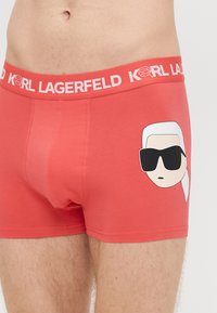 Boxers rouges en tissu doux, ornés d'un dessin animé sur le devant et d'une ceinture élastique avec logo imprimé.