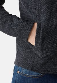 Dunkelgrauer Strickpullover aus strukturiertem Stoff mit einer Kängurutasche und abgerundetem Saum. Bietet eine lässige Passform und einen gerippten Ausschnitt.