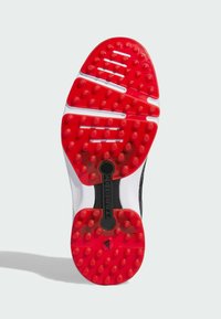 Podeszwa buta wykonana jest z czerwonej gumy z teksturowanymi wypustkami zapewniającymi przyczepność, białymi akcentami oraz centralnym czarnym, żebrowanym obszarem oznaczonym napisem "torfs".