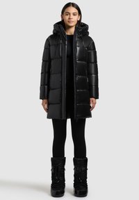 Sort pufferjakke med hætte, med en skinnende overflade, kviltet design og frontknapper. Sammen med sorte, teksturerede vinterstøvler.
