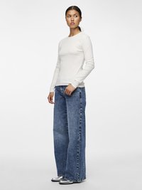 Pitkähihainen valkoinen ribbineulospaita yhdistetty korkeavyötäröisiin, leveälahkeisiin sinisiin farkkuihin. Asu sisältää hopeanväriset kengät, joissa on tyylikäs viimeistely.