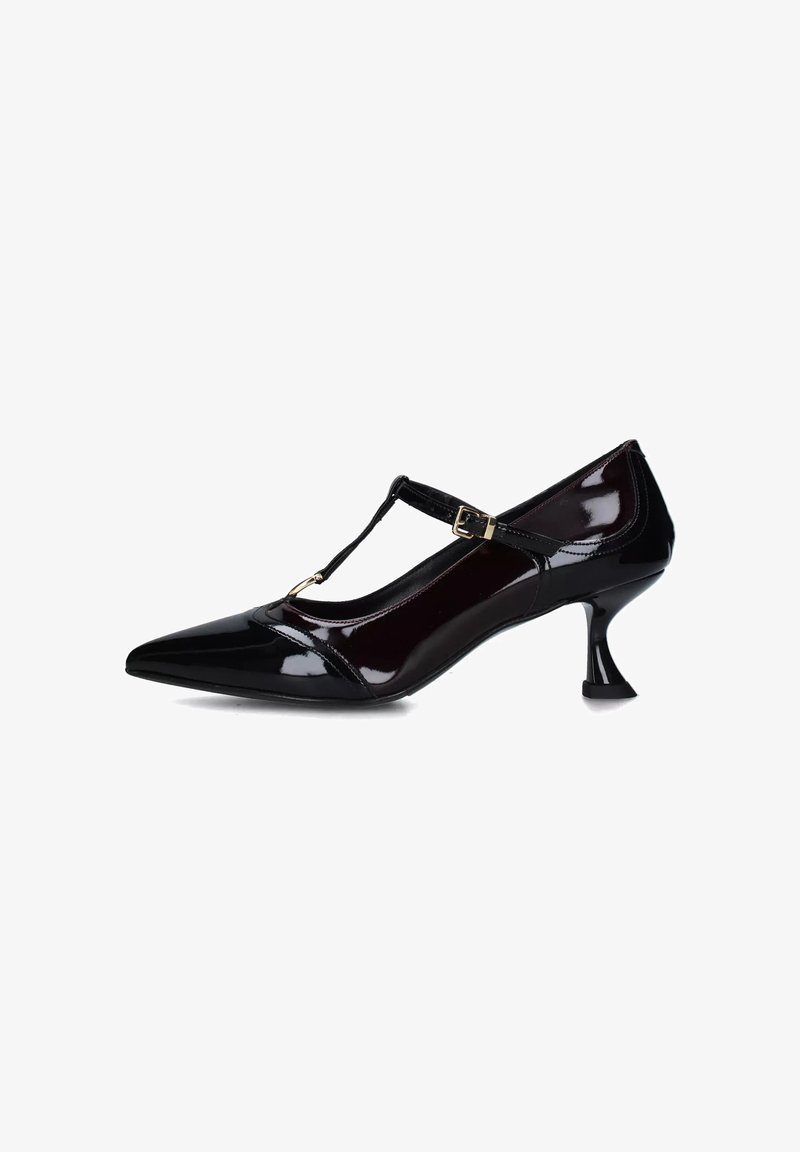 Scarpa con tacco alto in pelle patinata nera, con punta affusolata, design a T, fibbia regolabile e tacco curvo unico.