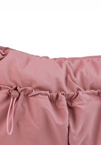 Tissu imperméable rose clair avec un cordon de serrage et un design froncé en haut. Texture lisse avec une apparence minimaliste.