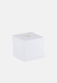 Boîte carrée blanche avec une finition texturée, présentant un logo triangulaire doré sur le dessus. La boîte a un couvercle avec charnière.