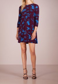 Blommig klänning med bordeauxbakgrund, prydd med livfulla blå blommor. Trekvartsärmar, vågad form, tillverkad av mjukt, lätt tyg.