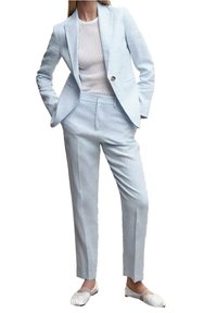 Costume bleu clair sur mesure avec blazer à un bouton, pantalon slim et haut blanc texturé à côtes. Porté avec des chaussures blanches plates.