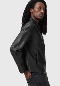 Black leather jacket with a smooth texture, zipper closure, and side pockets. Features a classic collar and a fitted silhouette.