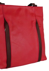 Rode synthetische leren draagtas met bruine leren accenten en stiksels. Heeft een strak, hoekig ontwerp. Gladde textuur met minimale hardware.