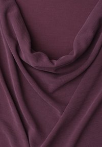 Tissu doux et drapé de couleur prune atténuée avec une texture de tissage fin visible et des plis délicats créant des courbes et des ombres douces.