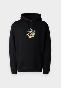 Svart huvtröja med en framficka, som har en färgglad grafik av en fågel och en banner med texten "Santa Cruz". Tillverkad av en bomullsblandning, i pullover-stil.