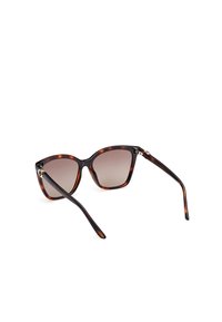 Ochelari de soare din material tortoiseshell cu design cat-eye, lentile gradient și brațe negre elegante. Prezintă accente metalice discrete la balamale.