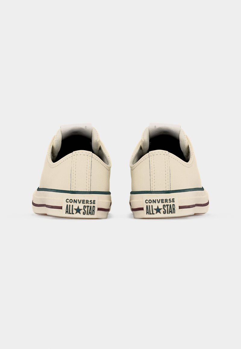 Paar off-white Converse All Star Low-Top-Sneaker, Rückansicht, mit schwarzen und dunkelroten Streifen an den Sohlen.