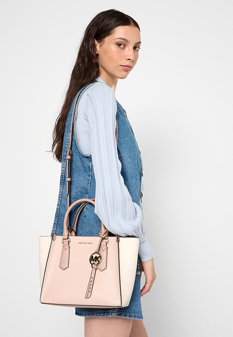 Rosa- und cremefarbene Lederhandtasche mit strukturiertem Format, doppeltengriffen und einem Logo-Schlüsselanhänger. Verfügt über eine glatte Textur und kontrastierende Kanten.