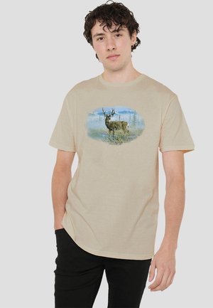 Beige cotton t-shirt with a deer graphic centered on the torso, featuring blue and green scenery. Short sleeves and crew neck design.
