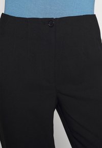 Svarta byxor i texturerad tyg med knappstängning och veck framtill. Designen är enkel och skräddarsydd för en välsittande look.