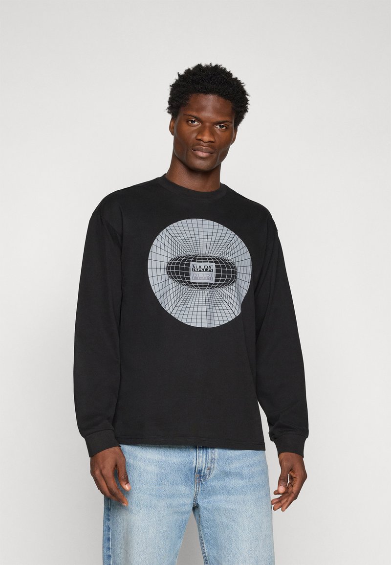 Camiseta negra de manga larga con un gran gráfico gris en el centro y un logotipo rectangular, combinada con jeans de mezclilla azul claro.