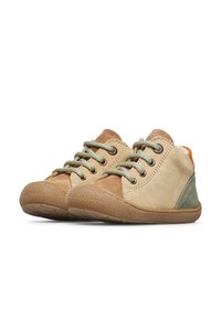 Zapatos de gamuza en color beige y marrón de talla infantil, con cordones, suelas de goma texturizadas y detalles en verde.