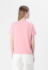 T-shirt rosa a maniche corte realizzato in morbido cotone, con scollo rotondo e vestibilità comoda. La vista posteriore presenta un design semplice senza motivi.
