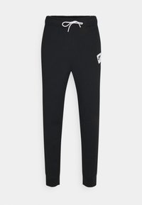 Svarta sweatpants i mjukt, elastiskt material med ett vitt dragsko vid midjan och en liten vit logopatch på vänster lår.