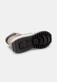 Chaussure en suede marron et mesh gris avec une semelle en caoutchouc noir texturé présentant un motif de semelle à relief chunky et des bords arrondis.