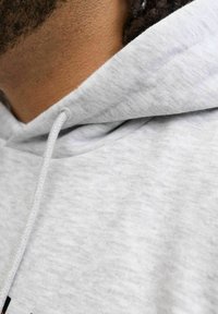 Lichtgrijze hoodie van een gestructureerde, zachte stof. Heeft een trekkoord bij de hals en een zichtbare, gestikte kraag.
