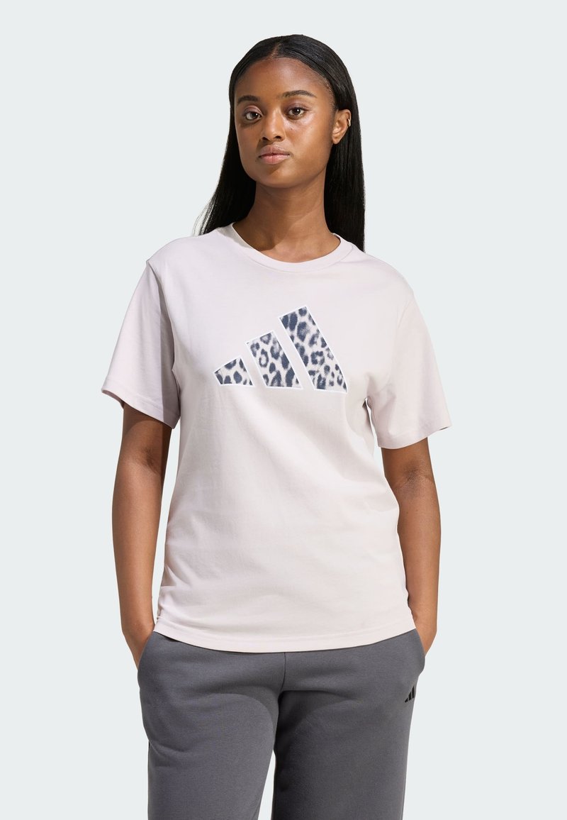 Světle růžové bavlněné tričko s leopardím potiskem loga Adidas. Kulatý výstřih a krátké rukávy. Kombinováno se šedými tepláky.