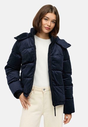 Veste matelassée bleu marine avec une finition texturée, fermeture éclair et capuche amovible. Comprend deux poches latérales et une silhouette ajustée.
