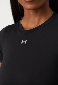 T-shirt preta ajustada de manga curta feita de um tecido suave, com decote redondo, apresentando um logo refletor prateado da Under Armour no peito.
