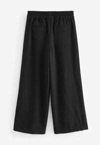 Schwarze weit geschnittene Hose mit elastischem Bund und zwei horizontalen Gesäßtaschen, vor weißem Hintergrund präsentiert.