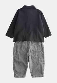 Czarna, długorękawowa koszulka polo zestawiona z paskowanymi czarno-białymi spodniami z wieloma kieszeniami i luźnym krojem.