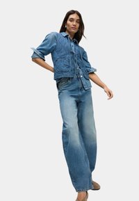 Jeansjacka med quiltat mönster, två framfickor; matchad med ljusblå, vida denim jeans. Båda har en mjuk textur.