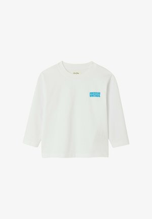 Biela tričko s dlhým rukávom a okrúhlym výstrihom s modrým nápisom „American Vintage“ na ľavej strane hrudníka, zobrazené na jednoduchom pozadí.