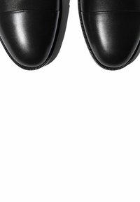 Zapatos de cuero negros con un acabado suave y brillante. Punta redondeada, costuras mínimas y un leve tacón. La suela presenta un dibujo sutil para mayor tracción.