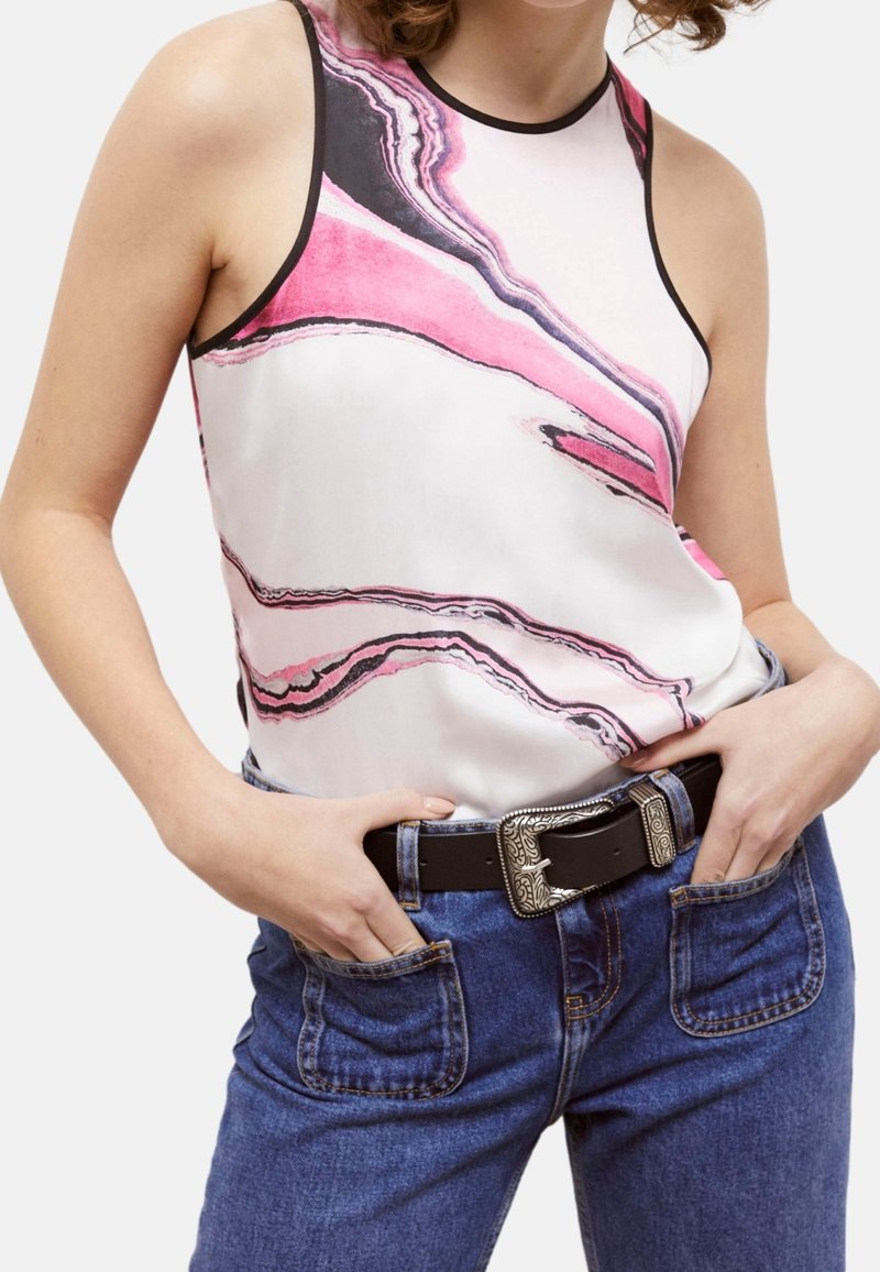 Débardeur en soie avec un motif marbré rose et blanc, bordé de noir, associé à un jean bleu taille haute et une ceinture noire.