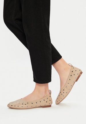 Beżowe baleriny z srebrnymi ćwiekami po bokach, płaską podeszwą i okrągłym noskiem. Noszone z czarnymi spodami 7/8.