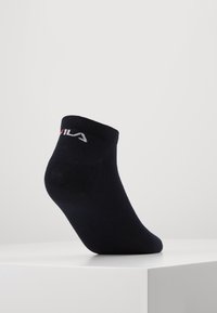 Marineblaue Knöchelsocken aus atmungsaktivem Material. Mit einem gerippten Bund und einem weißen Logo an der Seite. Glatte Textur, dehnbares Design.