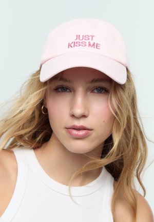 Cappellino da baseball rosa con testo ricamato "JUST KISS ME" in un font rosa scuro. Presenta un visiera curvata e un tessuto morbido.