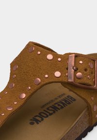 Καφέ σουέντ σανδάλι Birkenstock με χαλkινές διακοσμητικές καρφίτσες και ρυθμιζόμενο χαλkινό κούμπωμα σε φελλό σόλα.