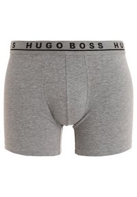 Graue Baumwollboxershorts mit einem schwarzen, gebrandeten Gummibund, auf dem der Text "HUGO BOSS" wiederholt ist. Glatte Textur und taillierte Passform.