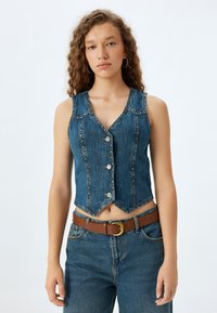 Gilet in denim con un design aderente, chiusura a bottoni e orlo a punta. Caratterizzato da un lavaggio blu e cuciture decorative. Abbinato a una cintura.
