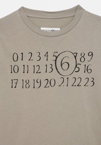 Ανοιχτό γκρι μπλουζάκι με τύπωμα αριθμών σε μαύρο, με ένα εμφανές κύκλο γύρω από τον αριθμό έξι. Στρογγυλή λαιμόκοψη.