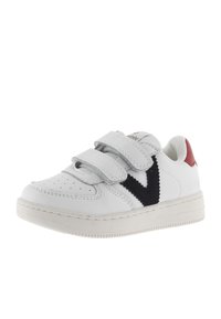 Baskets en cuir blanc avec deux bandes Velcro réglables, logo en forme de V noir, accent de talon rouge et semelle en caoutchouc texturé.