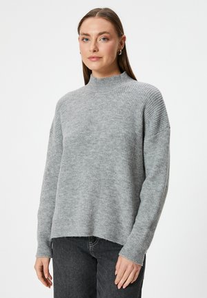 Pull en maille côtelée gris à col montant avec manches longues et coupe décontractée, présentant un ourlet court et un matériau texturé.