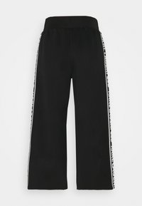 Czarne spodnie o szerokich nogawkach, wykonane z gładkiego materiału, z szerokim paskiem w talii i białymi paskami bocznymi z tekstem. Brak widocznych wzorów lub akcentów.