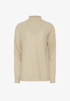 Beige ribbad stickad tröja med långa ärmar och en kort framdragkedja som sträcker sig till en hög krage, lös passform.