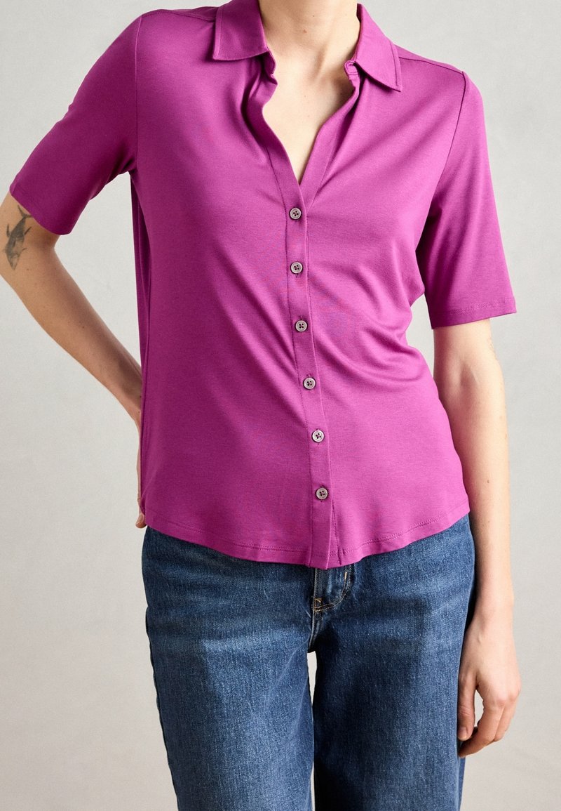 Korte mouw, knoopsluiting shirt in levendig magenta, met een klassieke kraag, een gladde textuur en een subtiele glans. Gepaard met denim.