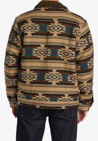 Wool-blend jacket featuring a brown, tan, and teal geometric pattern, with a sherpa collar and button cuffs. Designed with a relaxed fit.