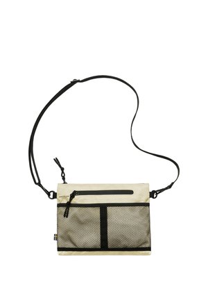 Kompaktowa beżowa torba na ramię z czarną siateczkową przednią kieszenią, kieszeniami na zamek, regulowanym czarnym paskiem oraz małą szwedzką flagą na boku.