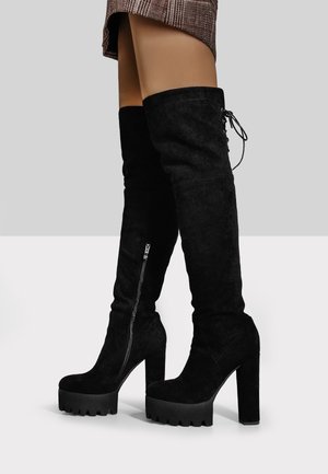 Black over-the-knee boots made of suede, featuring a thick platform sole, pointed toe, and a side zipper for easy wear.